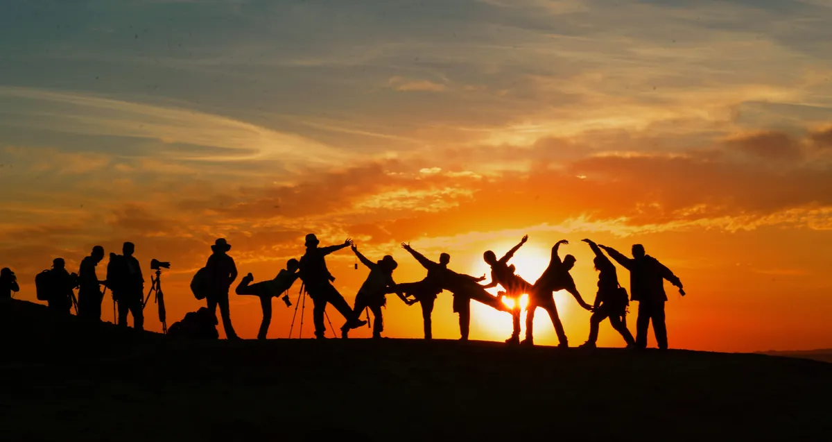 Grupo de viajantes em contraluz ao pôr do sol